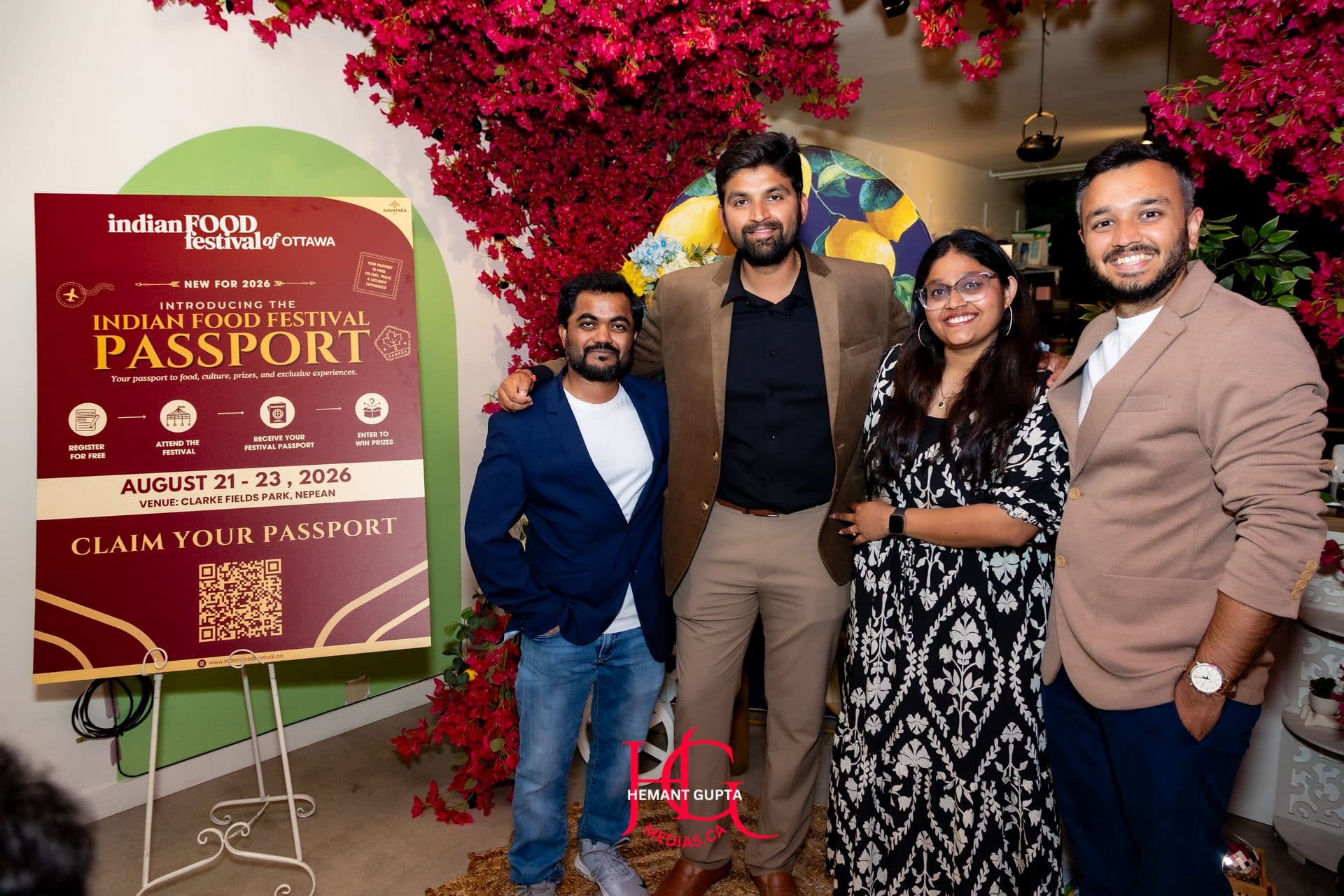 Four members of the Navatara team posing beside the Indian Food Festival Passport poster